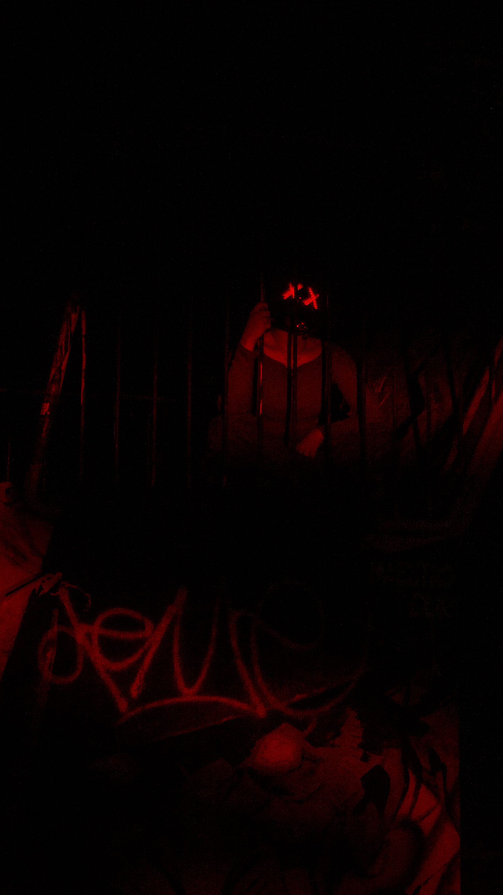 A woman with a cosplay cyberpunk mask with x lights on the led display near a graffiti wall