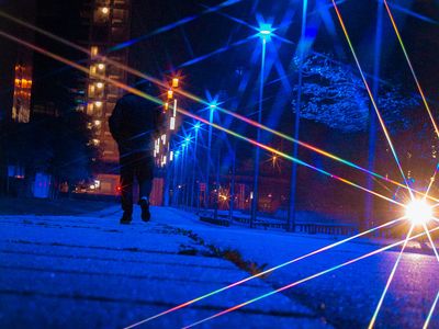 a man walking on the side walk with blue lights on the street